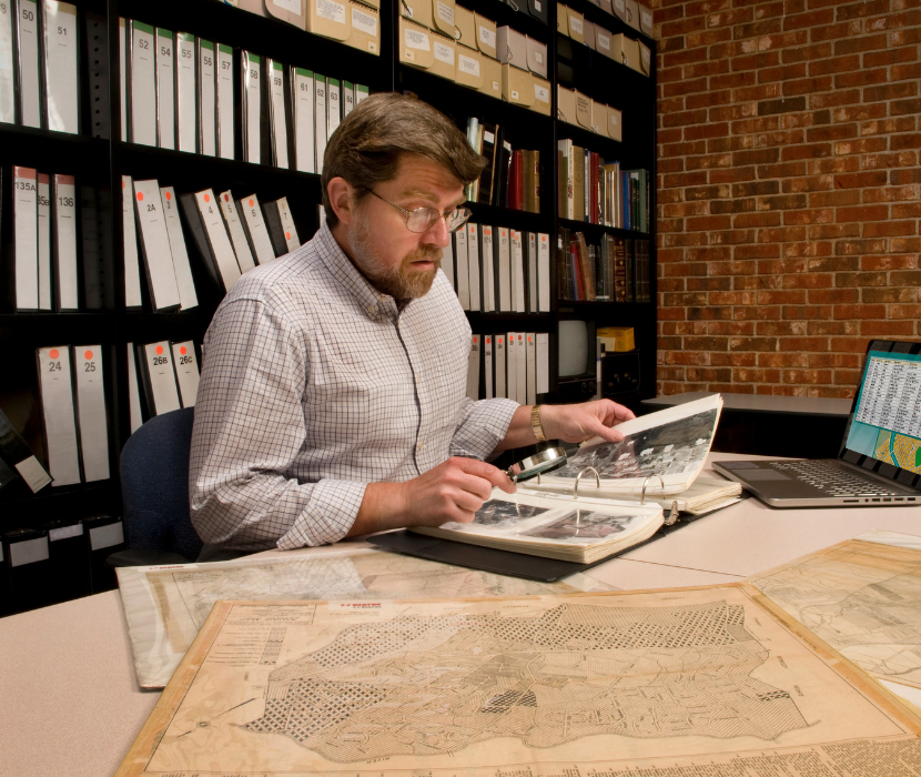 Man at Archive reviewing binder and historical maps