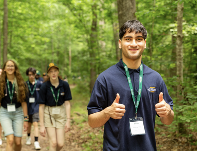 A National History Academy participant in a green polo giving two thumbs up.