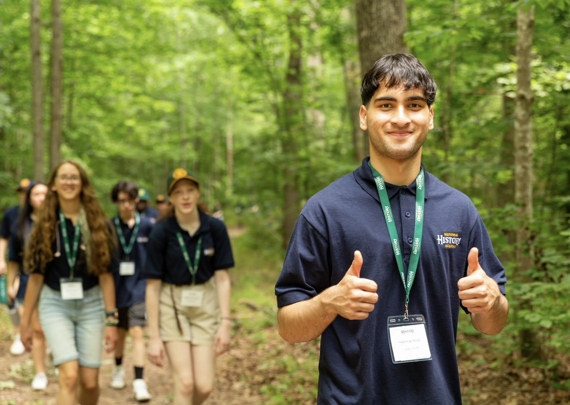 A National History Academy participant in a green polo giving two thumbs up.