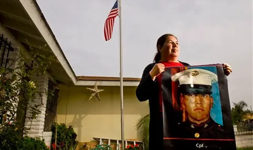 Photograph of Simona Garibay holding a banner of her son in front of US flag