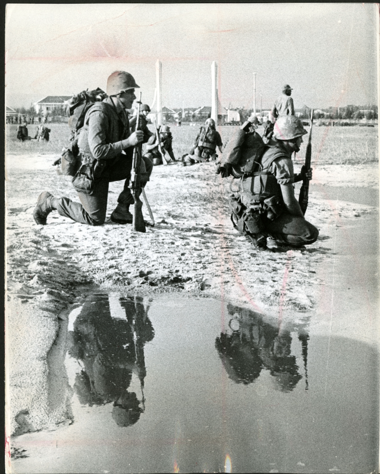 The Vietnam War (Black and white photo of Vietnam soldiers kneeling near a puddle of water that mirrors thier position)