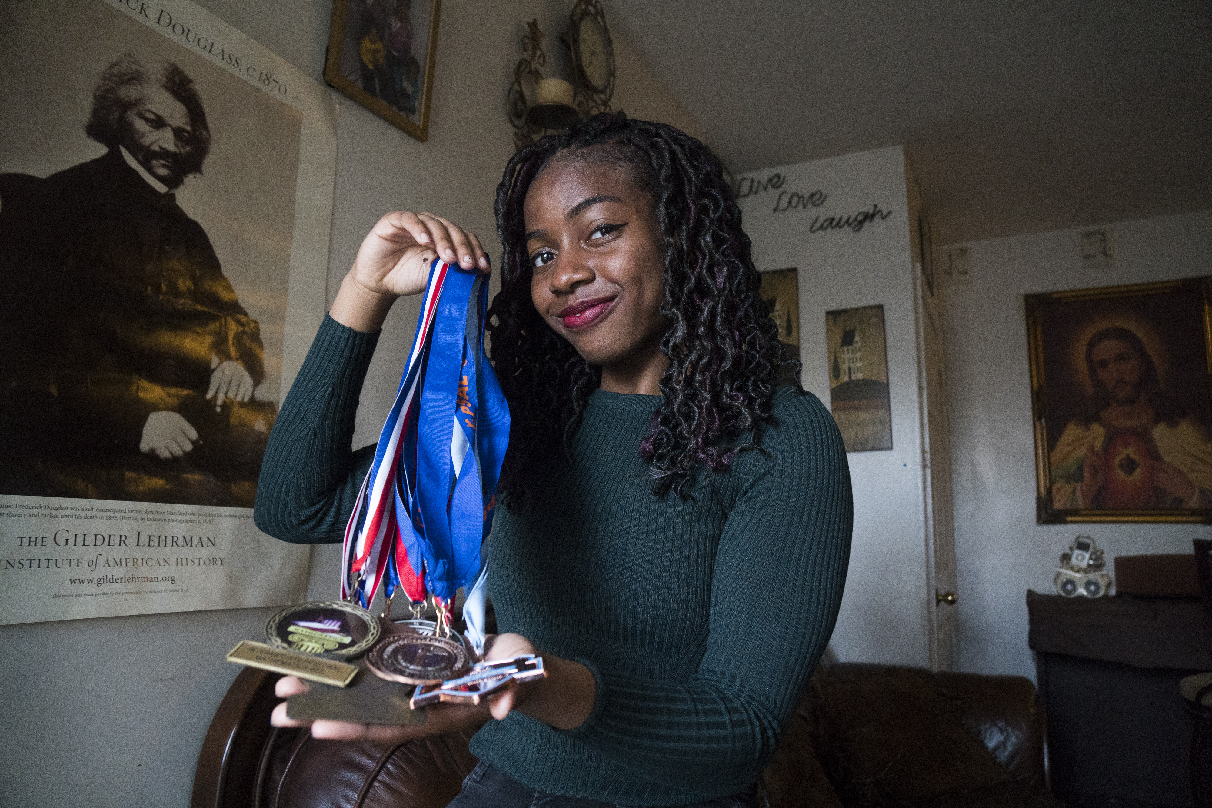 Venus Nnadi holding up medals in her Queens home (Go Nakamura/New York Daily News)