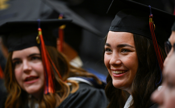 View of two graduating MA program students in cap and gown (one in the foreground, the other in the background) at the inaugural Gettysburg Commencement Ceremony