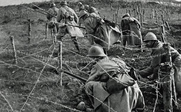 Soldiers crawling under barbed wire during World War I