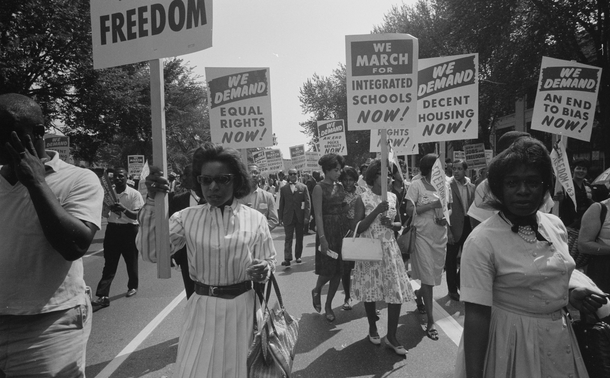 Men and women hold signs calling for equal rights in protest during the civil rights movement