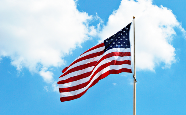 An American flag waves against a blue sky