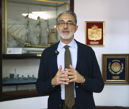 naval historian speaking in front of model ship