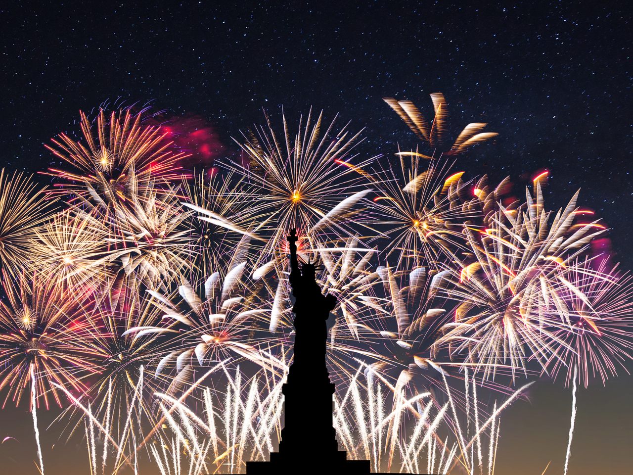 Fireworks in the background with silhouette of statue of liberty in foreground