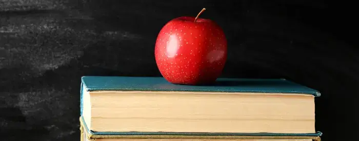 Apple on a stack of books in front of a chalkboard