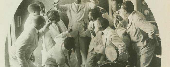 Photograph of James Reese with his band. He is shown conducting as the band members point at him.