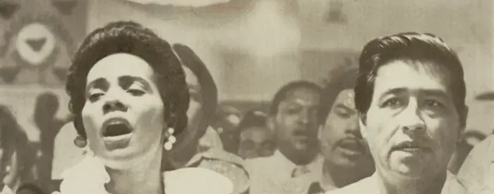 Photograph of Coretta Scott King and Cesar Chavez holding heads during a religious service