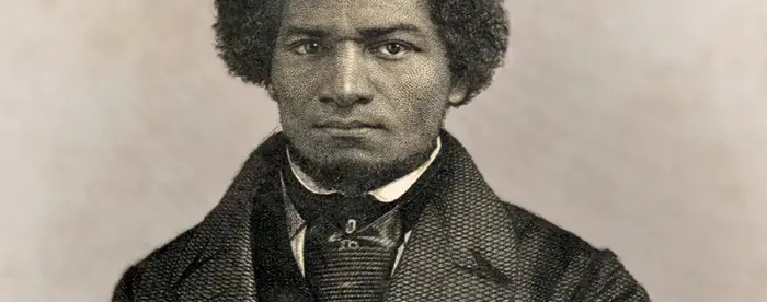 An engraving of Frederick Douglass as a young man, wearing a double-breasted jacket, vest or waistcoat, and scarf, looking fiercely into the camera