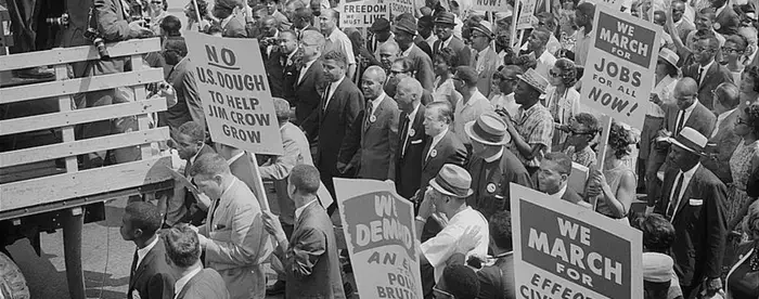 Photograph of civil rights leaders, including Martin Luther King, Jr., surrounded by crowds carrying signs.