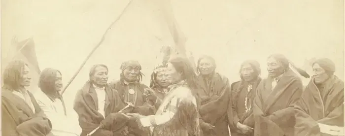 A group photograph of Lakota chiefs standing in front of tipi.