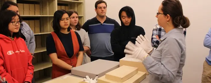 Students gathered around a table with historical documents laid out