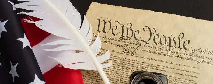 A quill laying across the Constitution