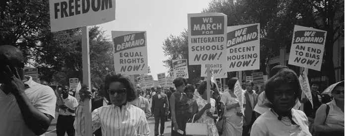 Men and women hold signs calling for equal rights in protest during the civil rights movement