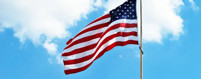 An American flag waves against a blue sky