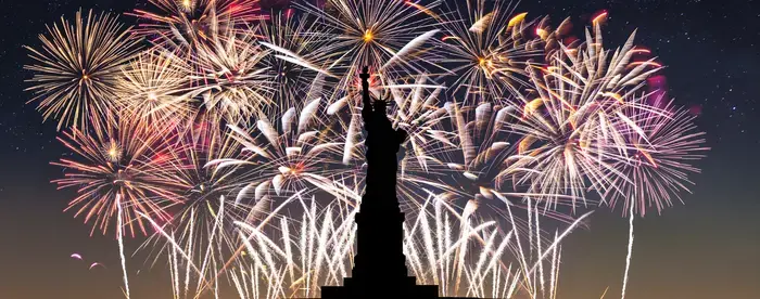 Fireworks in the background with silhouette of statue of liberty in foreground