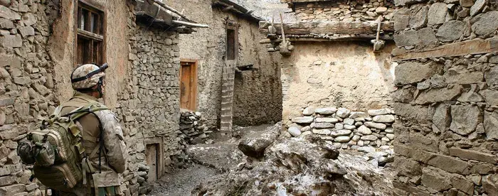 Soldier walking through alley between houses in desert terrain