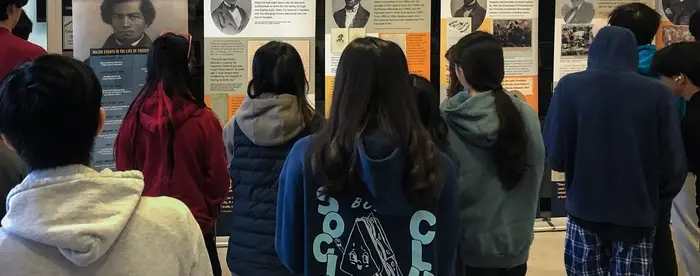 Students look at a historical traveling exhibition about the life of Frederick Douglass.