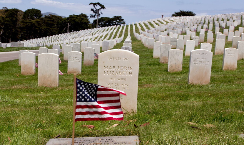 View of US flag in front of gravestones at a cemetery