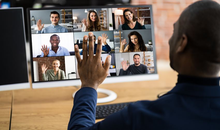 Man waving at computer with zoom session live and attendees waving back